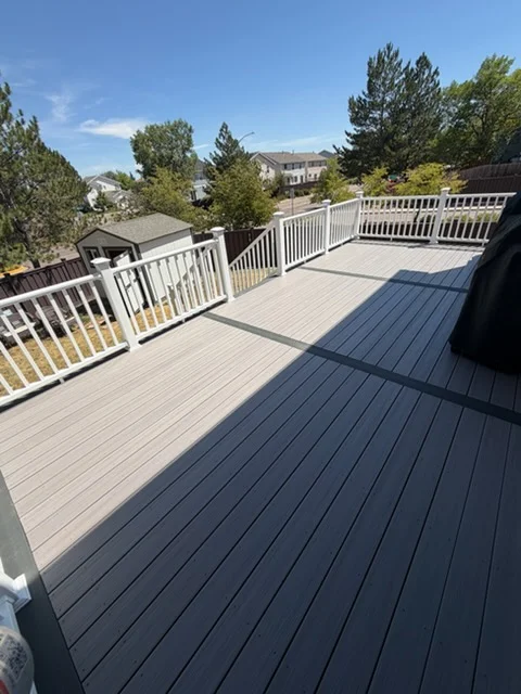 Two-tone composite deck with light and dark boards, white vinyl railings, elevated construction