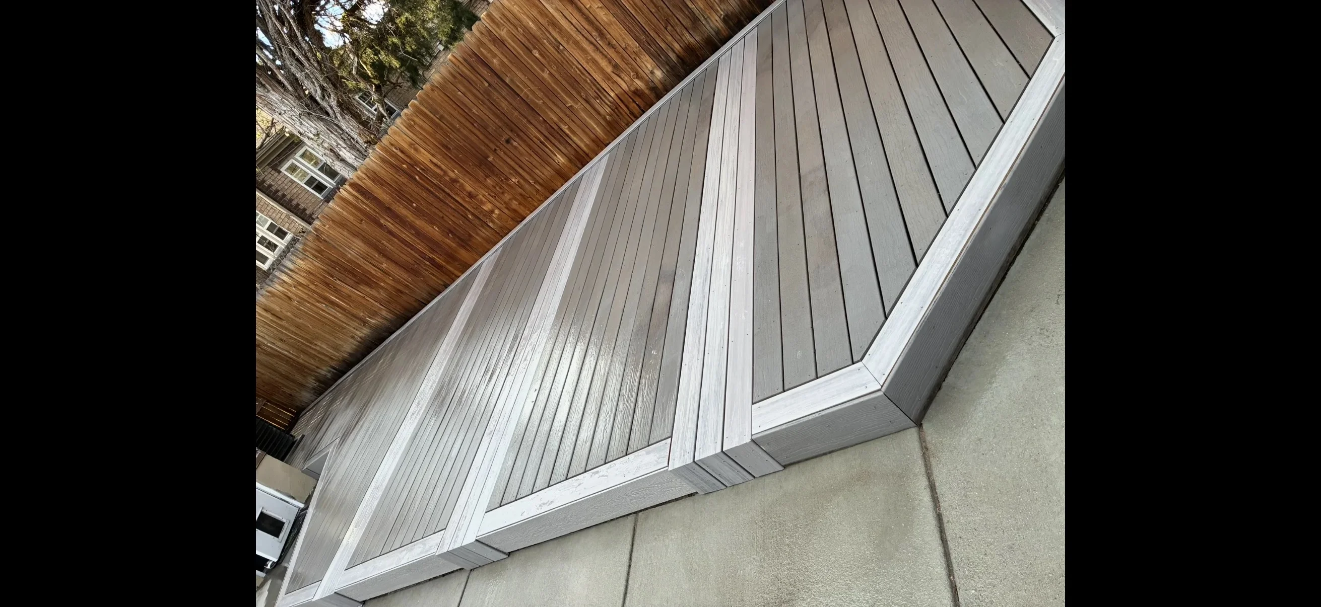 Gray composite deck with white trim and linear board pattern installation