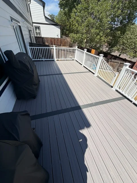 Two-tone composite deck with dark and light gray boards, white vinyl railing, and vertical balusters
