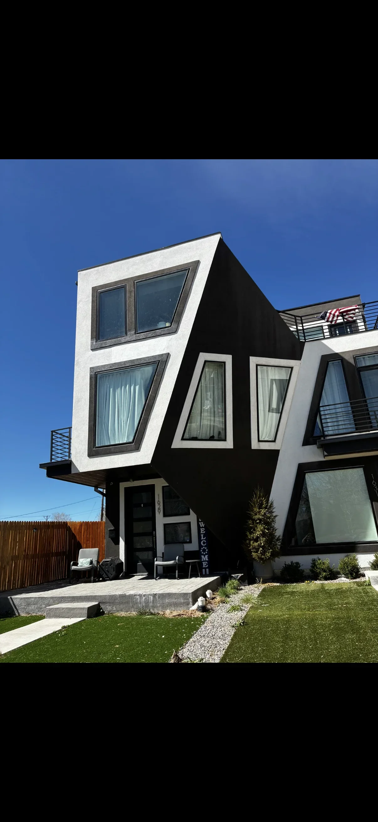 Modern home addition with black and white cladding, geometric windows, and metal deck railings