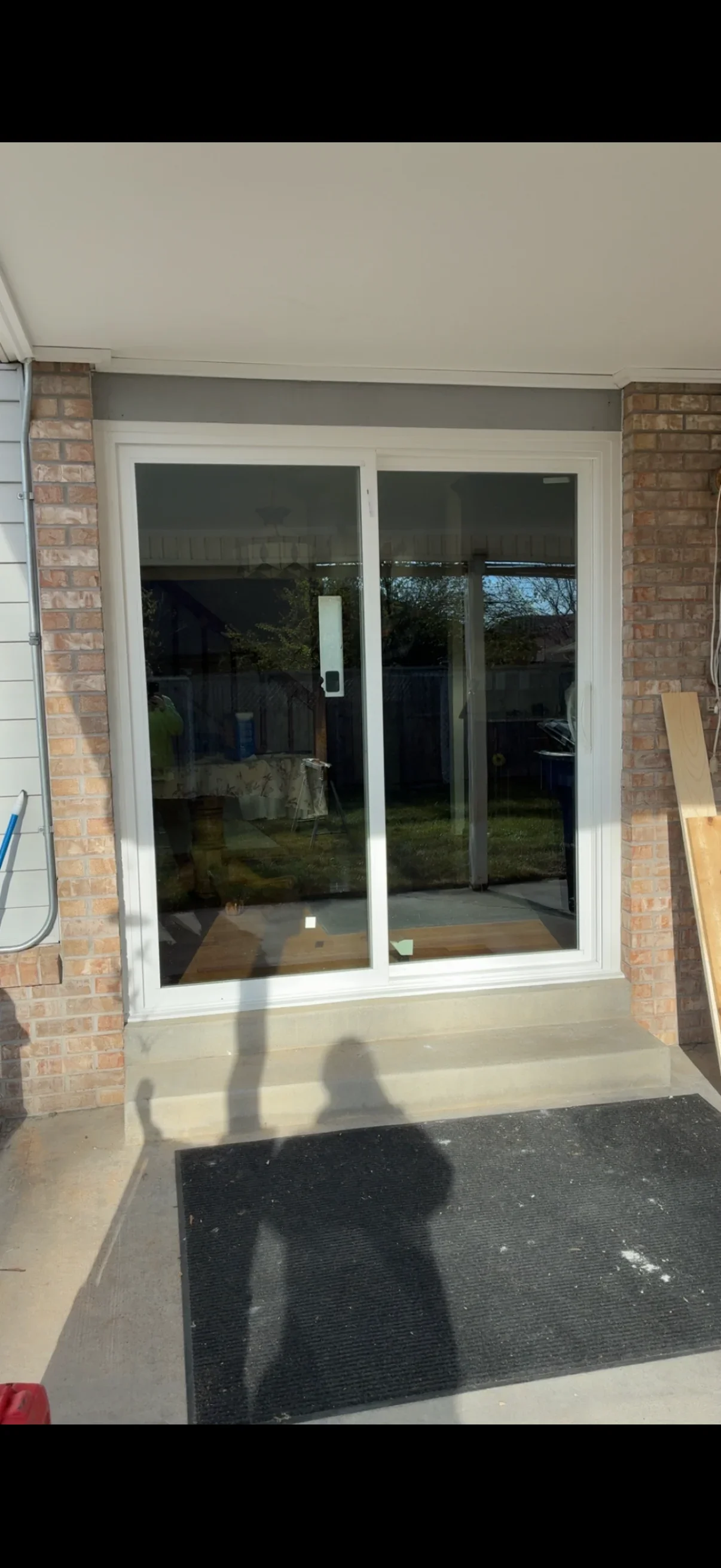 White-framed sliding glass door with dark tinted glass installed between brick columns