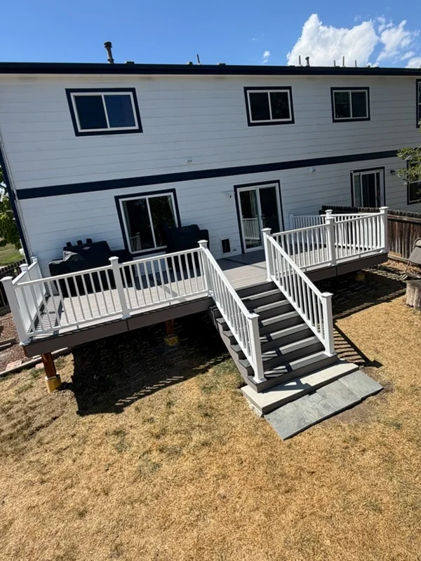 Two-level composite deck with white railings, black stairs, and ground landing