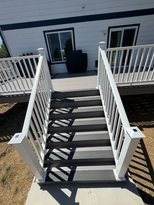 Gray composite deck with black stairs, white railings, and dual platforms leading to house
