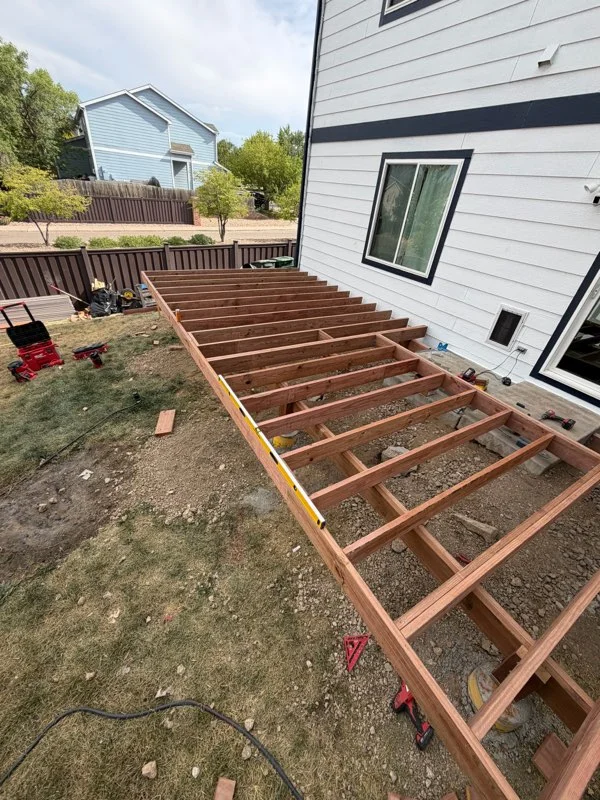 Pressure-treated wood deck frame with joists and gravel base during construction