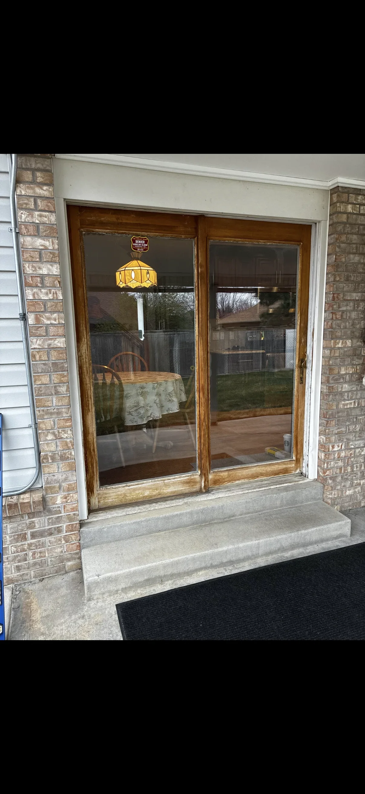 Wood-framed sliding glass patio doors with dark glass and white trim on brick exterior