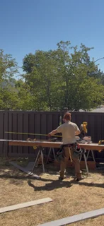 Deck framing with wooden joists, support posts, and structural beams under construction
