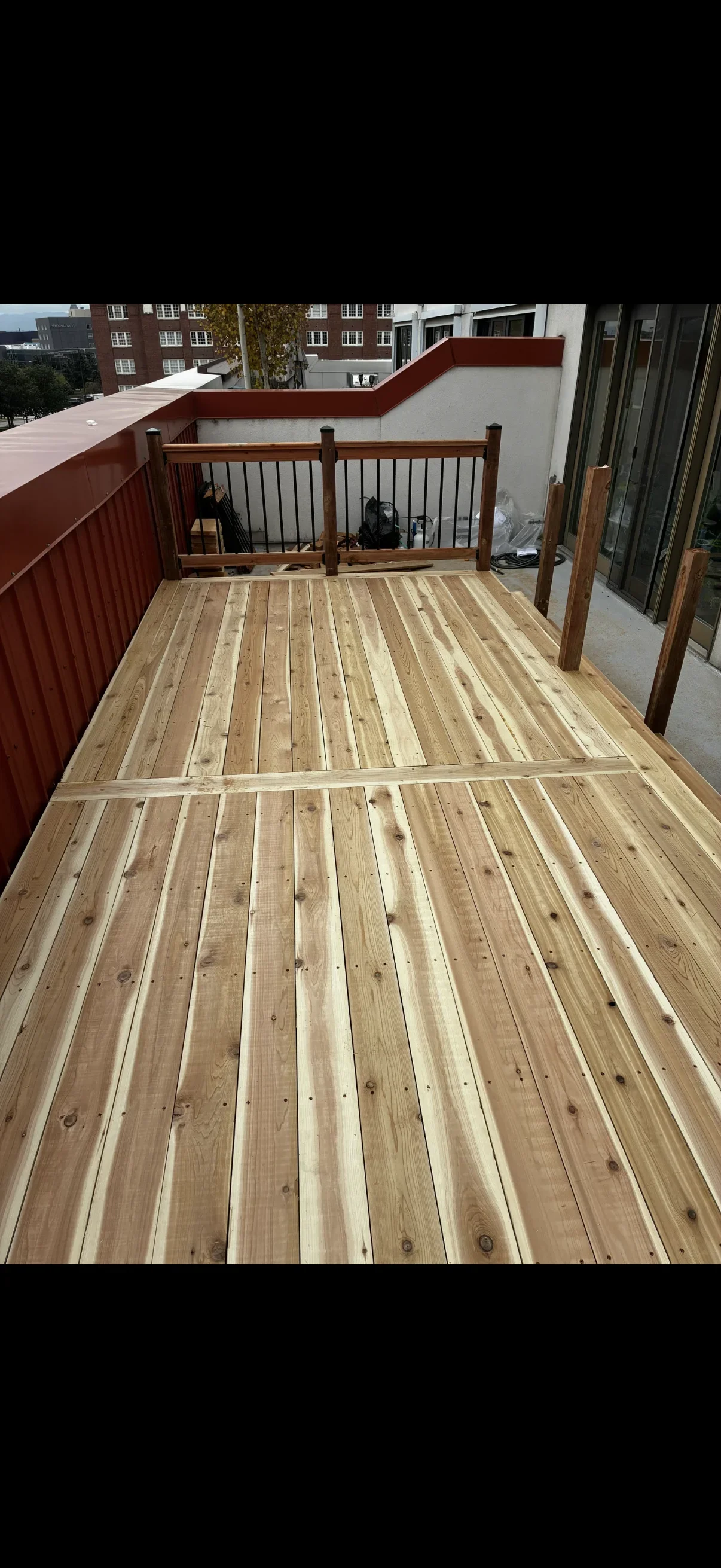 Newly installed pressure-treated wood deck with wooden railings and metal balusters on rooftop